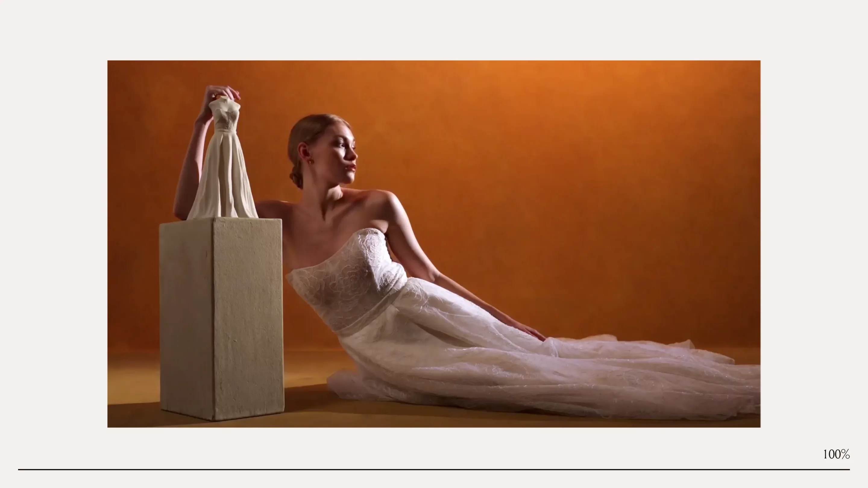 Vero New York home page: a model in a lace wedding gown reclines beside a small ceramic dress sculpture on a plinth, lit in warm orange against cream.
