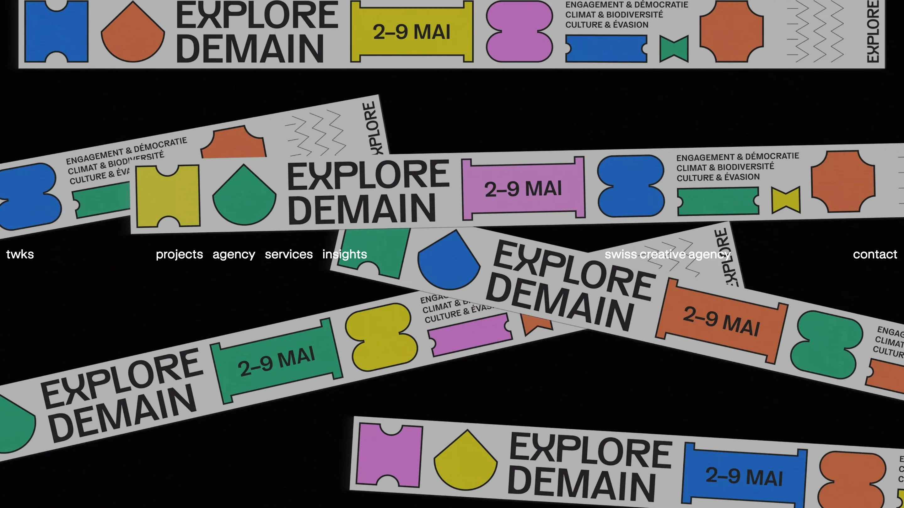 The twks home page with colourful Explore Demain festival banners laid at angles over black and a white navigation line
