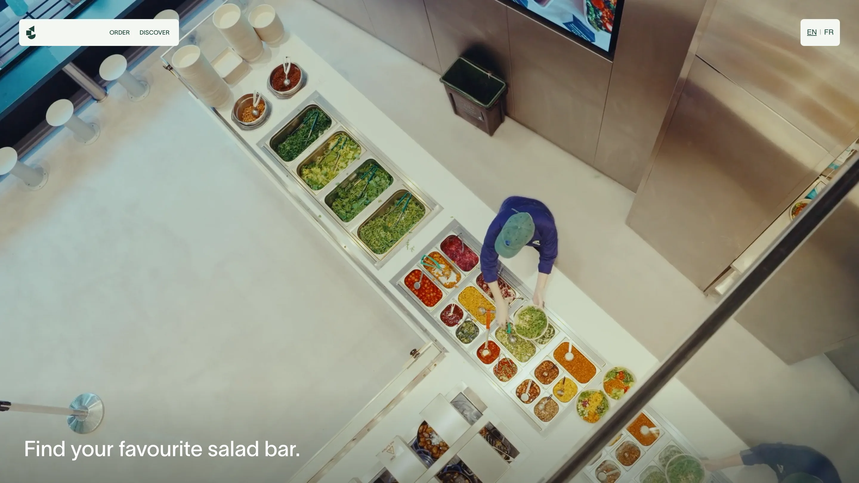 Overhead view of a Salad Project counter with a worker building bowls, captioned find your favourite salad bar