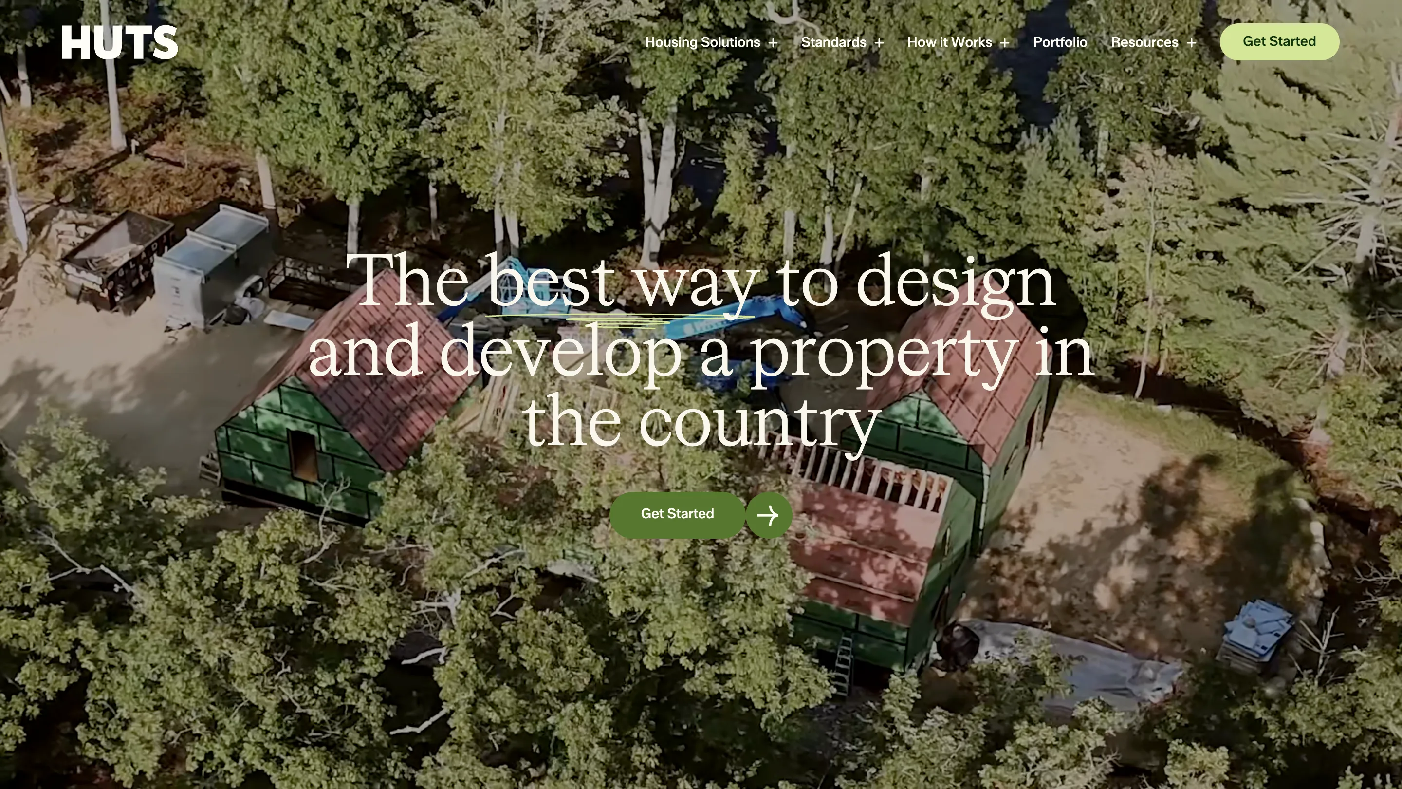 Huts homepage: an aerial photo of a green-roofed cabin in dense forest, with a large serif headline reading "The best way to design and develop a property in the country" and a green Get Started button