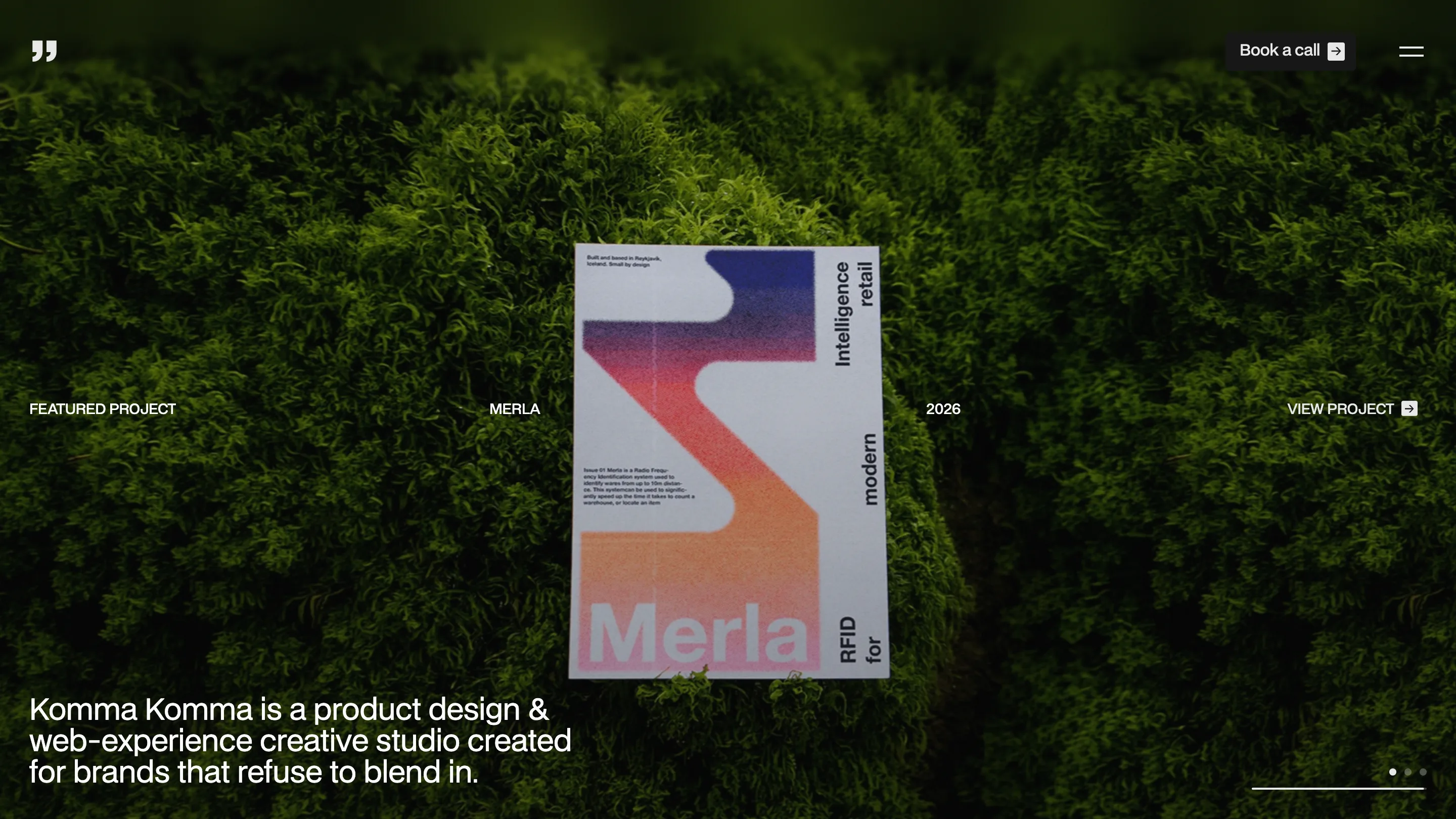 Komma Komma home page: a printed poster for the Merla project lying on green moss, with the studio tagline set in white below