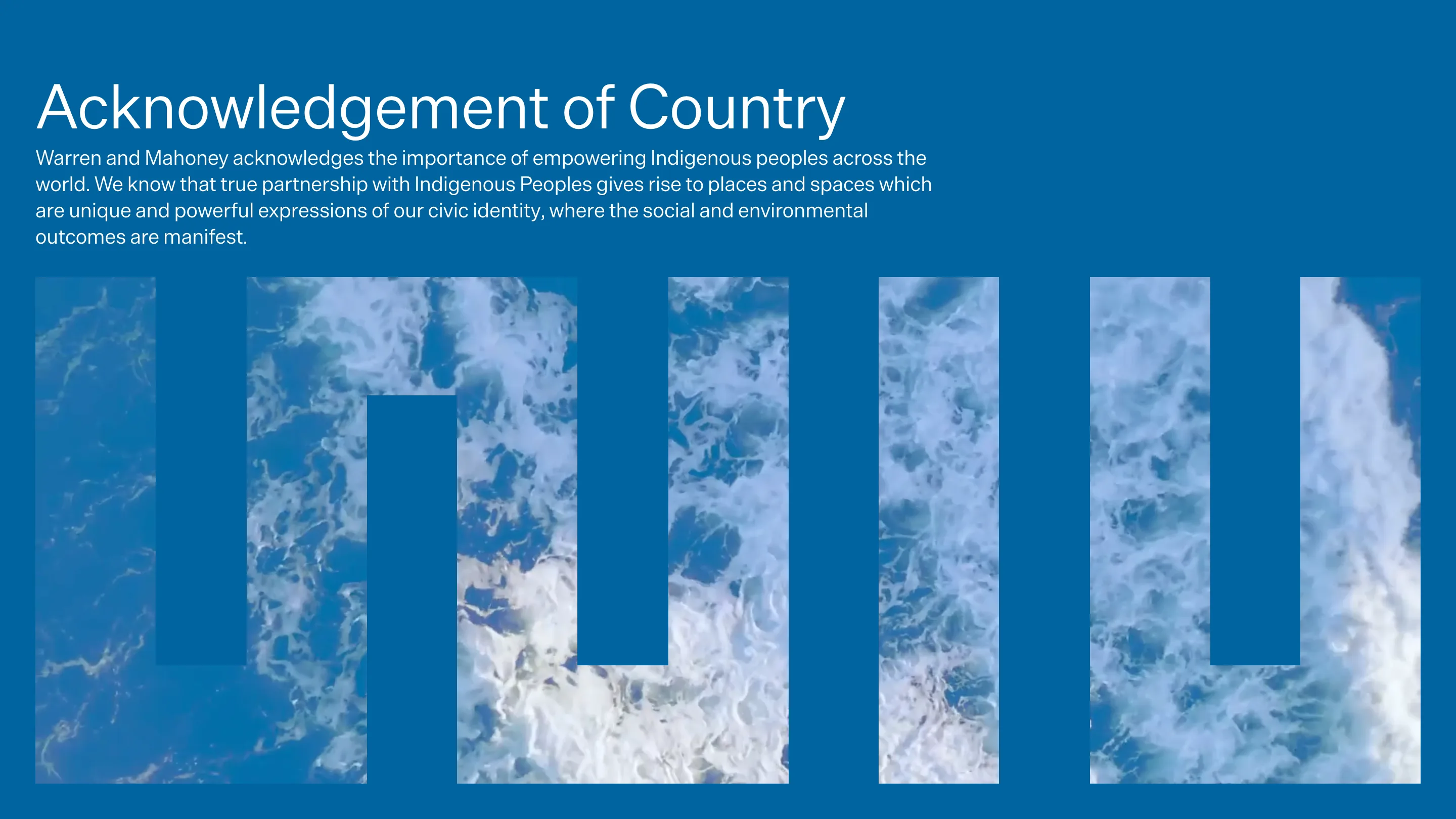 The Warren and Mahoney homepage: an Acknowledgement of Country headline on a cobalt blue field, with the practice's five-bar monogram below it cut out to reveal aerial footage of ocean surf