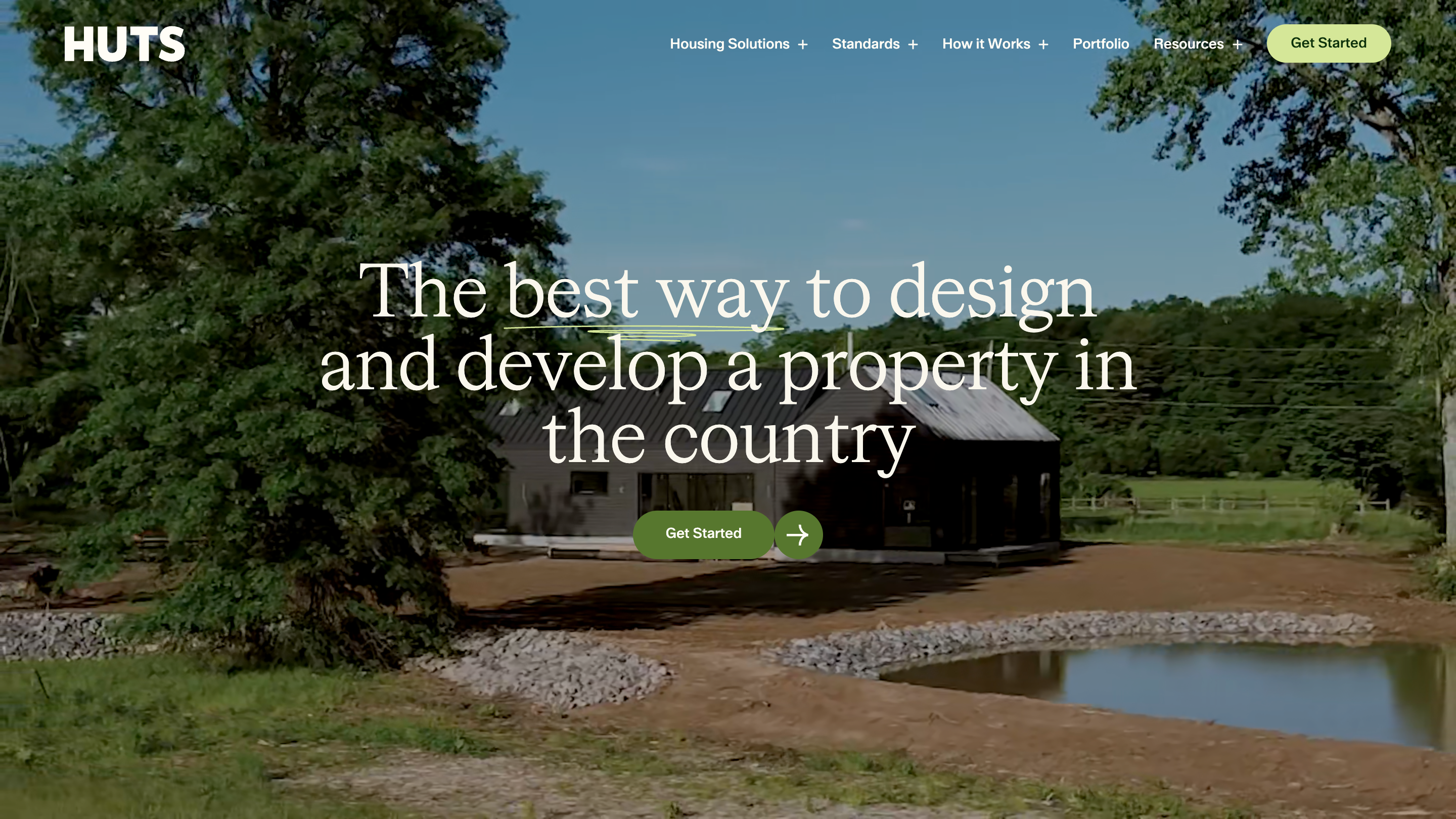 The Huts homepage: a video of a dark barn-shaped house beside a pond, with the serif headline "The best way to design and develop a property in the country" and a green Get Started button