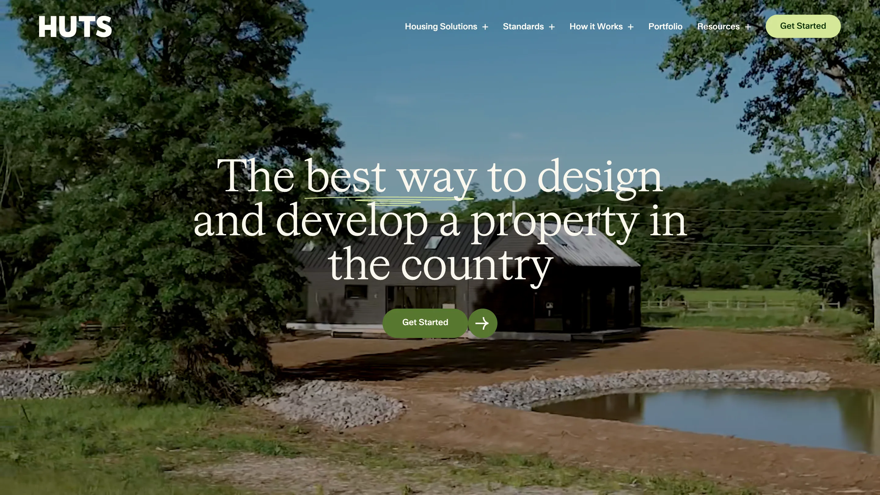 The Huts homepage: a video of a dark barn-shaped house beside a pond, with the serif headline "The best way to design and develop a property in the country" and a green Get Started button